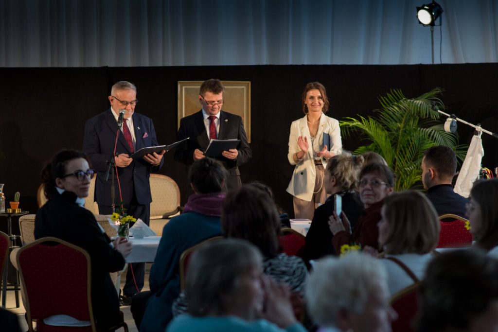 Mężczyźni w garniturze oraz kobieta w białym kostiumie